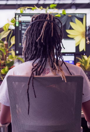 Foto de um homem de costas trabalhando em seu computador usando uma camiseta do Nubank